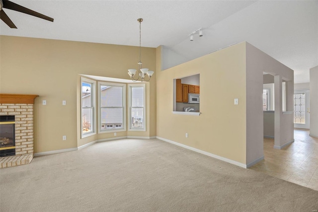 unfurnished living room featuring light carpet, lofted ceiling, ceiling fan with notable chandelier, a fireplace, and baseboards