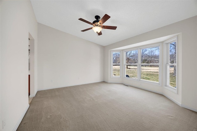 empty room with visible vents, light carpet, baseboards, ceiling fan, and vaulted ceiling