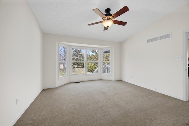 carpeted empty room featuring visible vents, baseboards, a ceiling fan, and vaulted ceiling