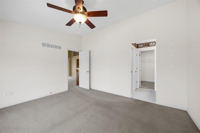 unfurnished bedroom with lofted ceiling, a spacious closet, visible vents, and carpet floors