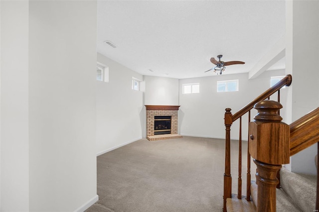 interior space featuring a ceiling fan, carpet, baseboards, and a fireplace