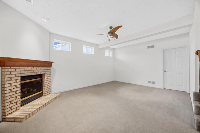 unfurnished living room with visible vents, a brick fireplace, carpet, and ceiling fan