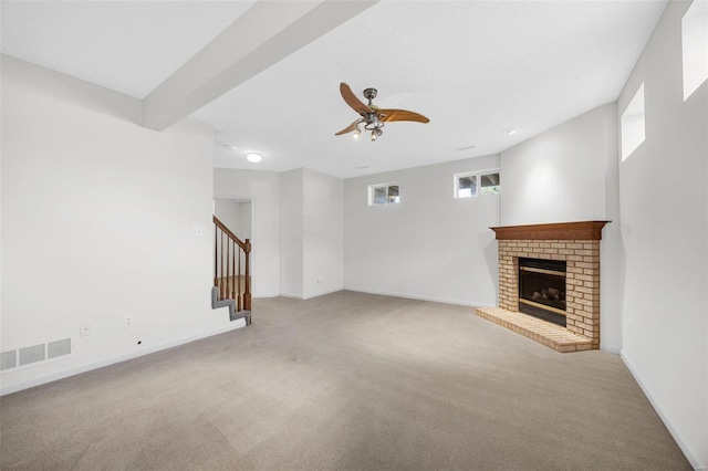 unfurnished living room with visible vents, stairway, carpet, a fireplace, and ceiling fan