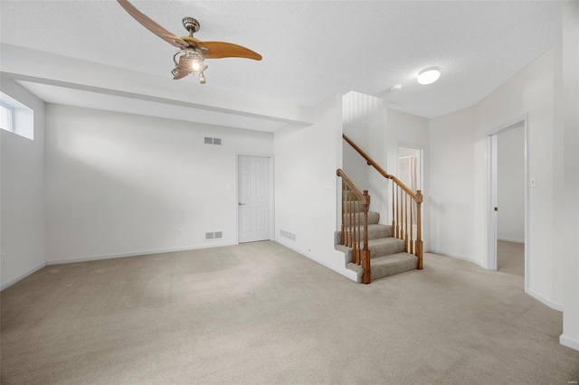 interior space featuring visible vents, stairway, carpet floors, a textured ceiling, and a ceiling fan