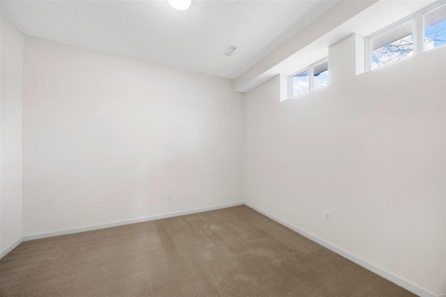 carpeted empty room featuring visible vents, baseboards, and a textured ceiling