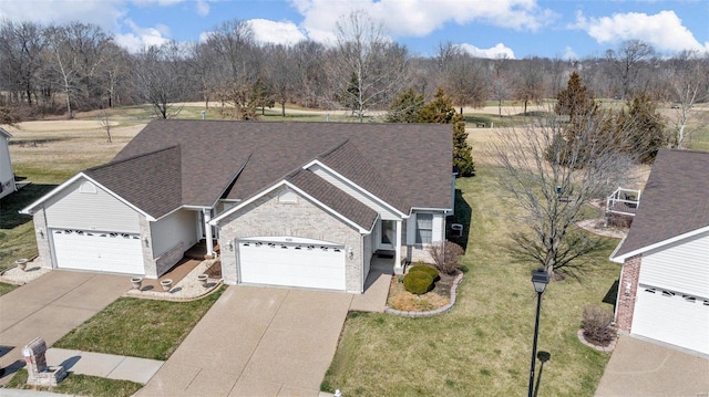 view of front facade with a front lawn, a garage, brick siding, and driveway