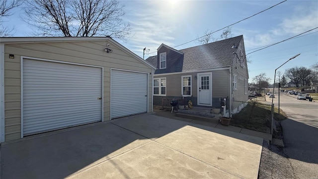 back of house featuring a detached garage, an outdoor structure, and roof with shingles