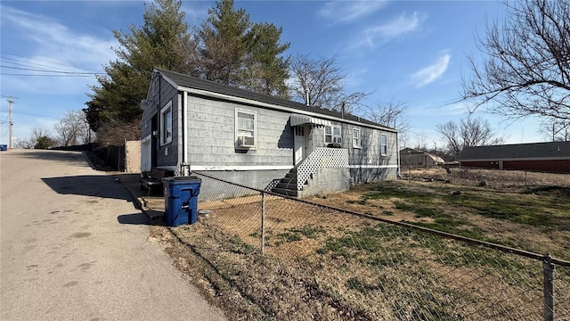 view of property exterior featuring cooling unit, driveway, and fence