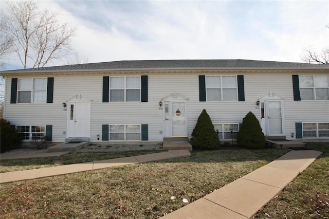 raised ranch with a front lawn and entry steps