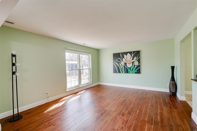 unfurnished living room featuring visible vents, baseboards, and hardwood / wood-style flooring