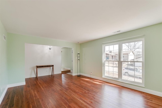 unfurnished living room with hardwood / wood-style flooring, baseboards, and visible vents