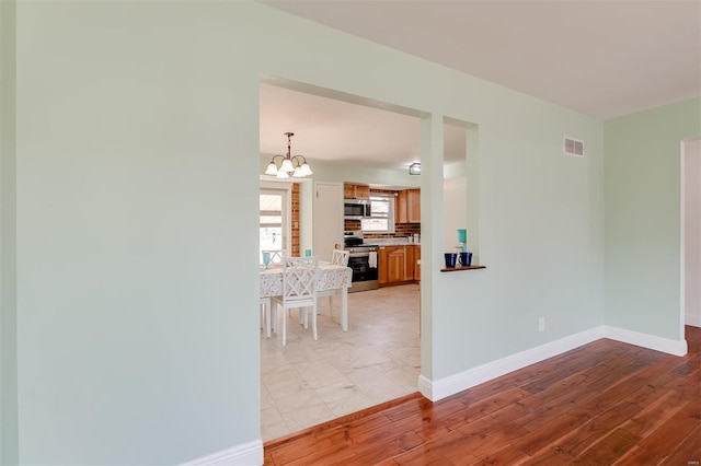 spare room featuring visible vents, baseboards, light wood-style floors, and a chandelier