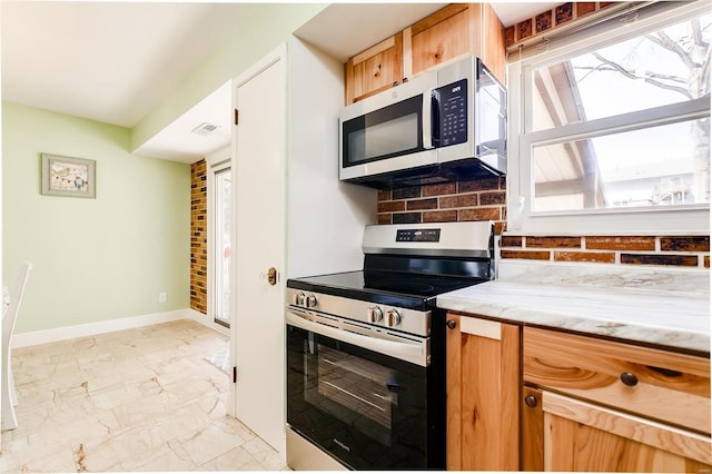 kitchen featuring light stone counters, baseboards, stainless steel appliances, marble finish floor, and backsplash