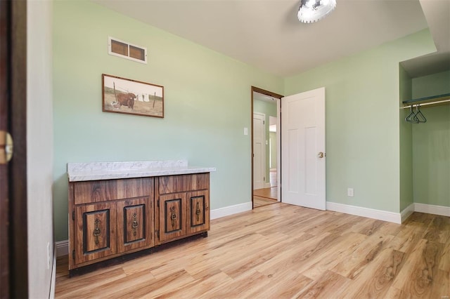 bedroom featuring a closet, visible vents, light wood-style flooring, and baseboards