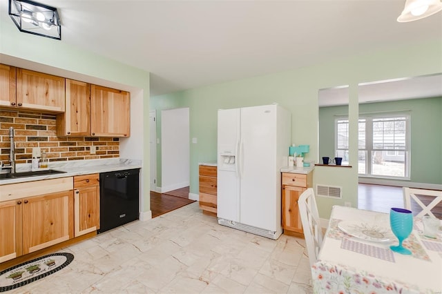 kitchen featuring a sink, white refrigerator with ice dispenser, marble finish floor, and black dishwasher