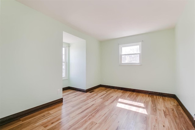 empty room featuring baseboards and light wood finished floors