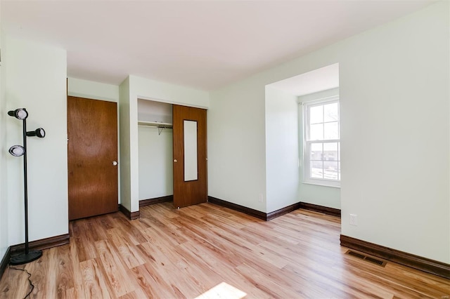 unfurnished bedroom with a closet, visible vents, light wood-style flooring, and baseboards