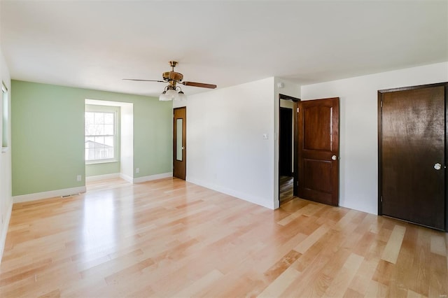 interior space with a ceiling fan, baseboards, and light wood-type flooring