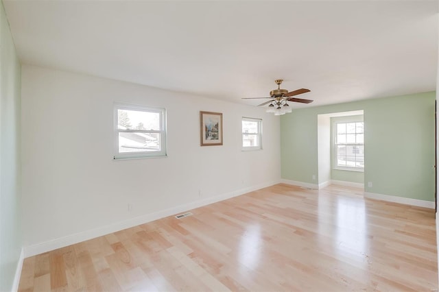 unfurnished room featuring light wood finished floors, visible vents, a ceiling fan, and baseboards