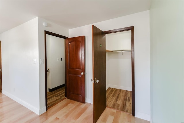 unfurnished bedroom with light wood finished floors, baseboards, and a closet