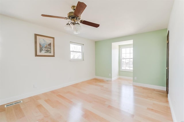 empty room featuring a wealth of natural light, visible vents, baseboards, and light wood-style floors