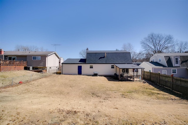 rear view of house featuring central air condition unit, a fenced backyard, and a shingled roof