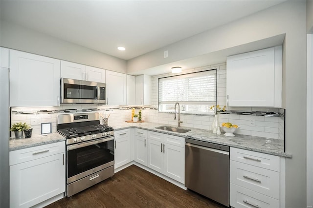 kitchen featuring a sink, stainless steel appliances, dark wood-style floors, and decorative backsplash