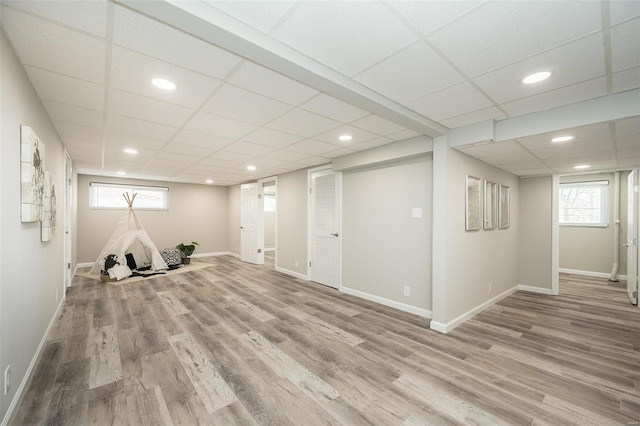 below grade area with a drop ceiling, recessed lighting, baseboards, and wood finished floors