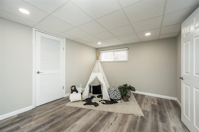 rec room with a paneled ceiling, baseboards, and wood finished floors