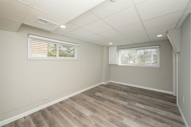 empty room with wood finished floors, baseboards, visible vents, recessed lighting, and a drop ceiling