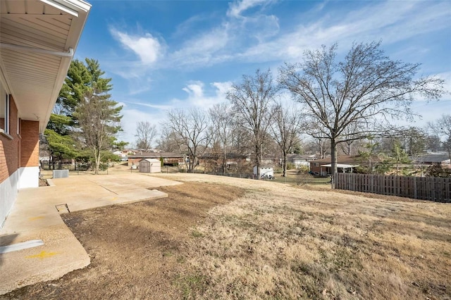 view of yard featuring a patio area, fence, an outbuilding, and a shed