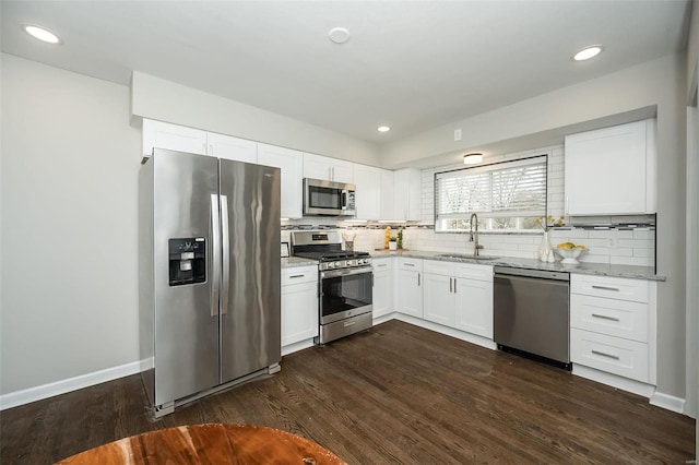 kitchen featuring dark wood finished floors, decorative backsplash, stainless steel appliances, and a sink