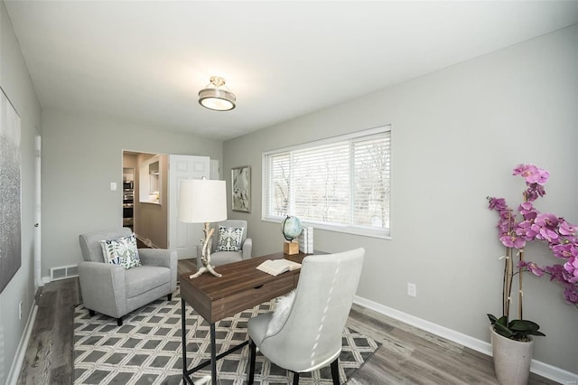 office area featuring visible vents, baseboards, and wood finished floors