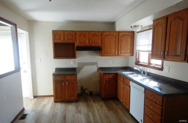 kitchen with a sink, visible vents, light wood-style flooring, and white dishwasher