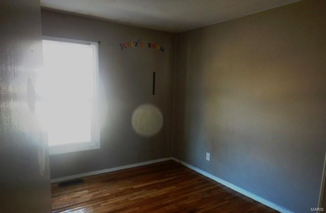 empty room featuring dark wood-style floors and baseboards