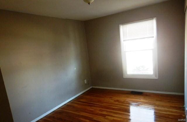 empty room with baseboards and dark wood-type flooring