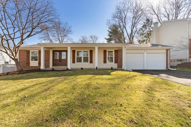 ranch-style home with aphalt driveway, a front yard, a garage, and brick siding