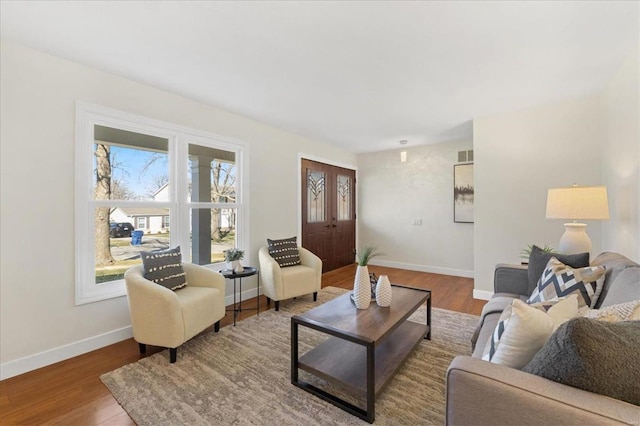 living room with visible vents, baseboards, and wood finished floors