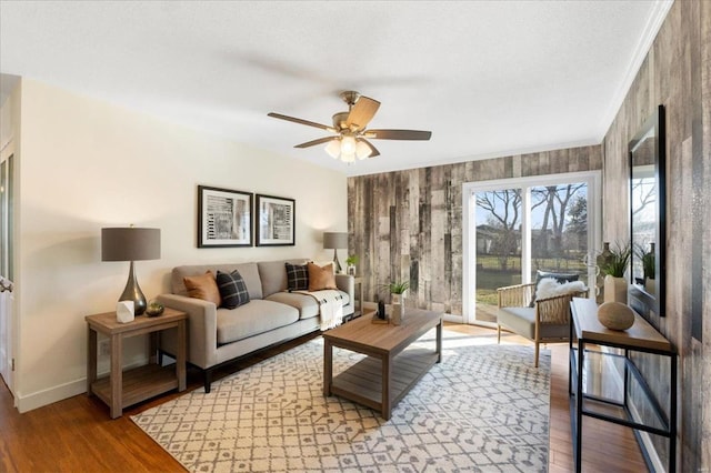 living room with baseboards, ceiling fan, ornamental molding, and light wood finished floors