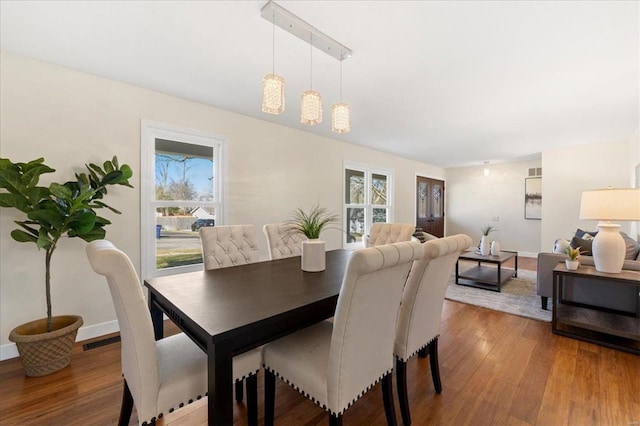 dining room featuring visible vents, baseboards, and wood finished floors