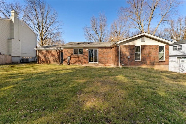 rear view of property with central AC unit, a yard, fence, and brick siding