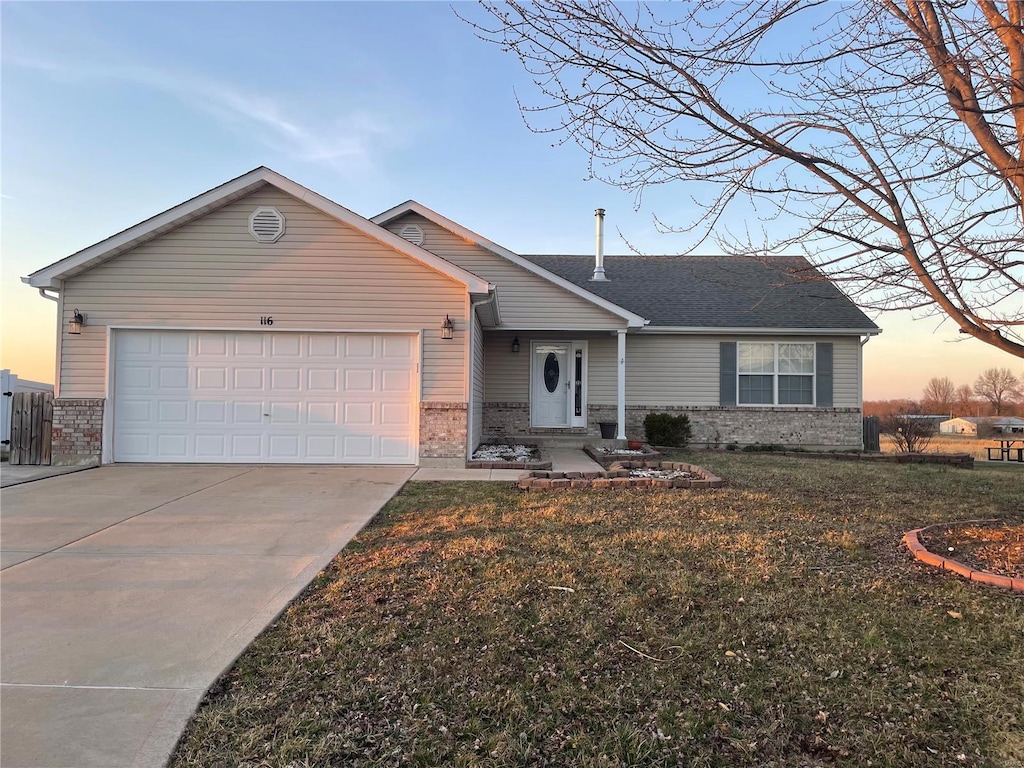 ranch-style home with a front lawn, brick siding, an attached garage, and driveway