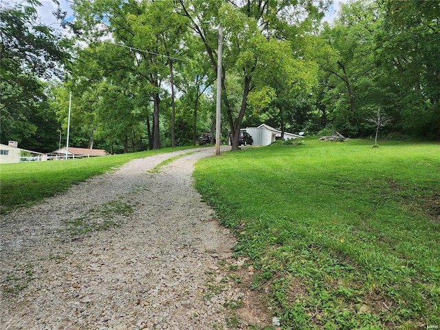 view of road with gravel driveway and a wooded view