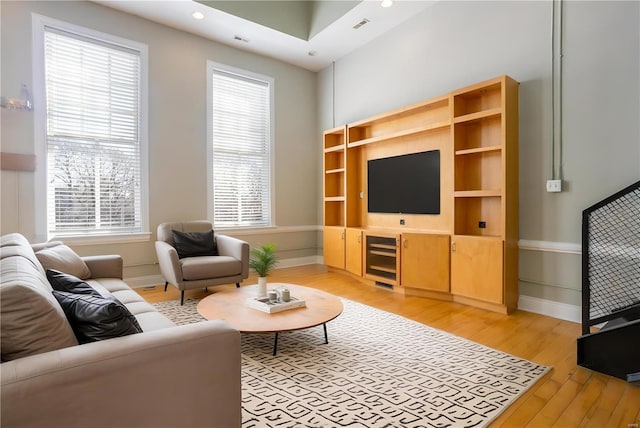 living area with wine cooler, light wood-type flooring, baseboards, and visible vents