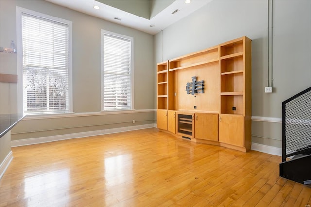 unfurnished living room featuring visible vents, baseboards, beverage cooler, and light wood-style flooring