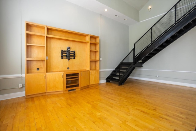 unfurnished living room featuring stairway, recessed lighting, baseboards, and hardwood / wood-style floors