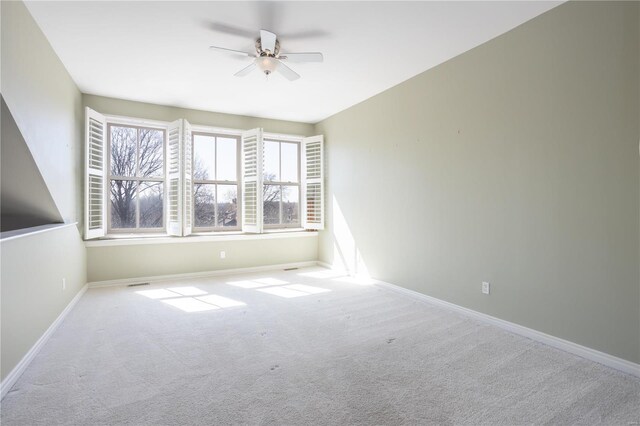 carpeted empty room with ceiling fan and baseboards