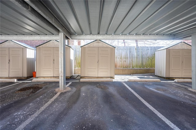 garage with a storage shed, covered parking, and fence