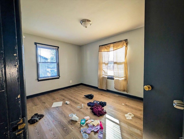 unfurnished bedroom featuring baseboards, multiple windows, and wood finished floors