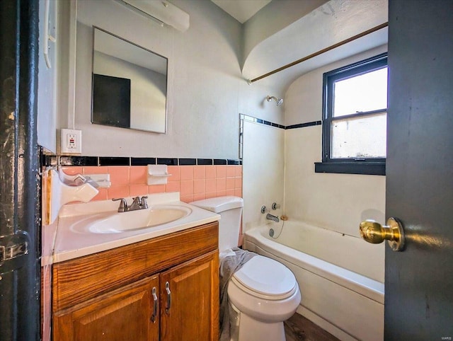 bathroom featuring bathing tub / shower combination, tile walls, vanity, and toilet